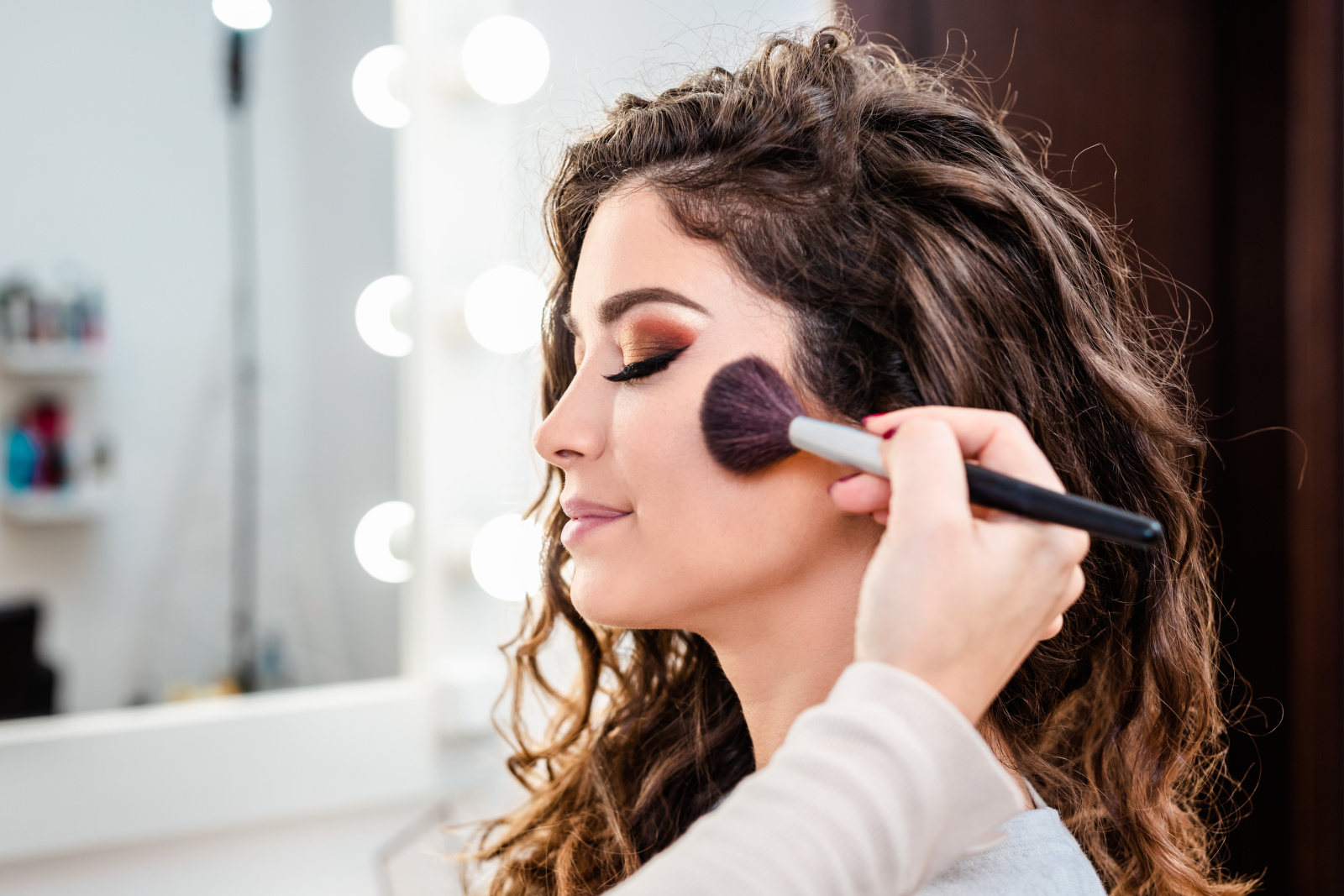 Make-up-Künstlerin wendet professionelles Make-up einer schönen jungen Frau an.